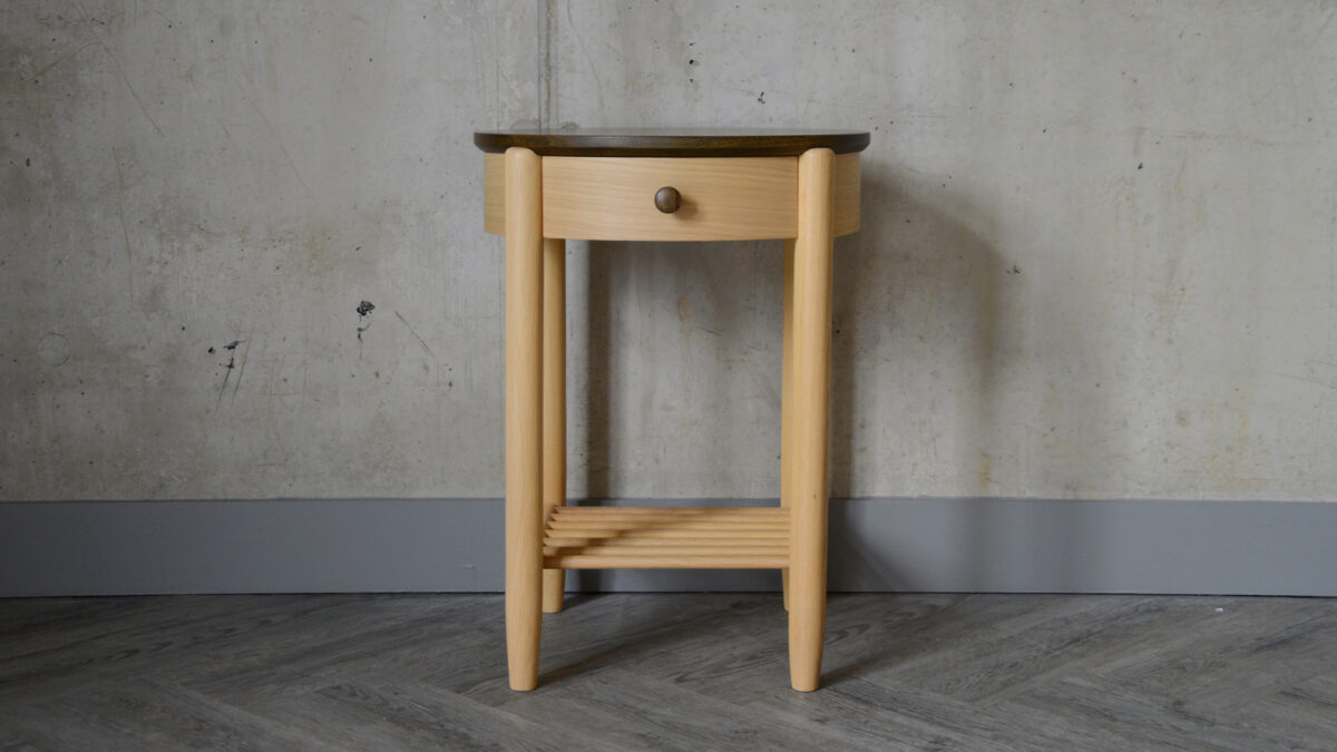 Arts and Craft style circular bedside table with drawer in a natural oak with a dark stained top