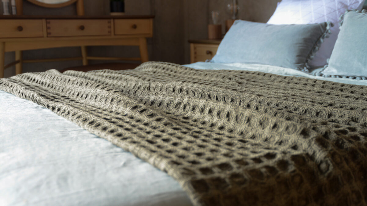 textured weave throw in olive green shown on a bed