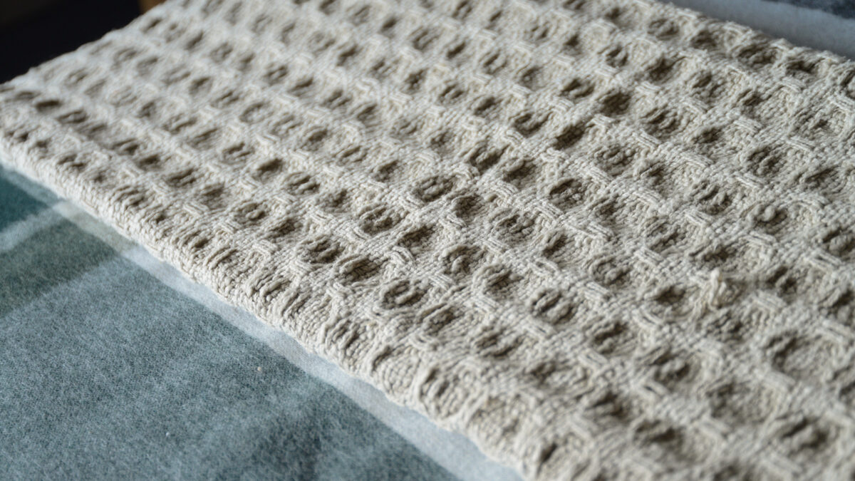 textured weave fringe edged throw in a beige colour