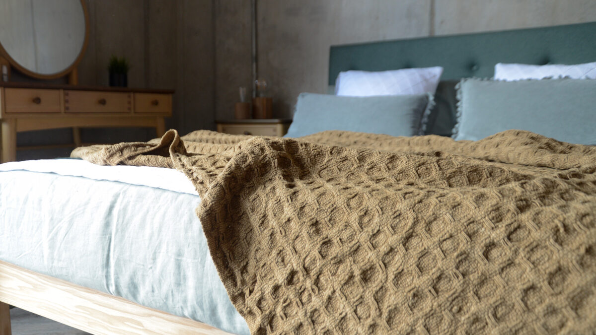 Textured weave throw in caramel brown shown on a bed