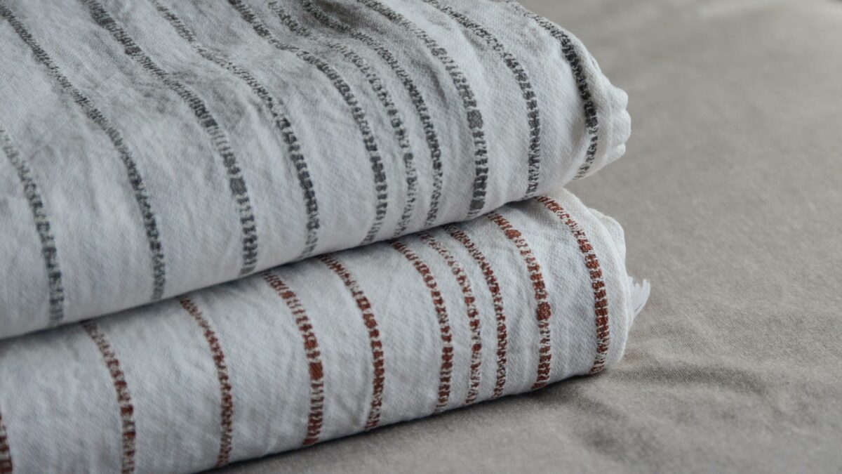 Woven white cotton throws with stripe in charcoal or terracotta