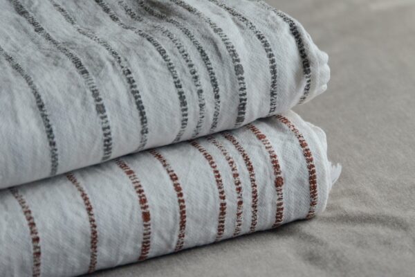 Woven white cotton throws with stripe in charcoal or terracotta