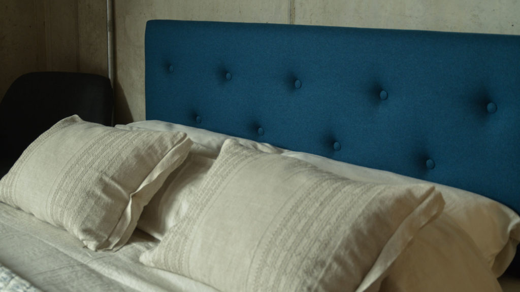 A closer view of the Arran buttoned upholstered headboard covered in amatheon marine-blue wool fabric