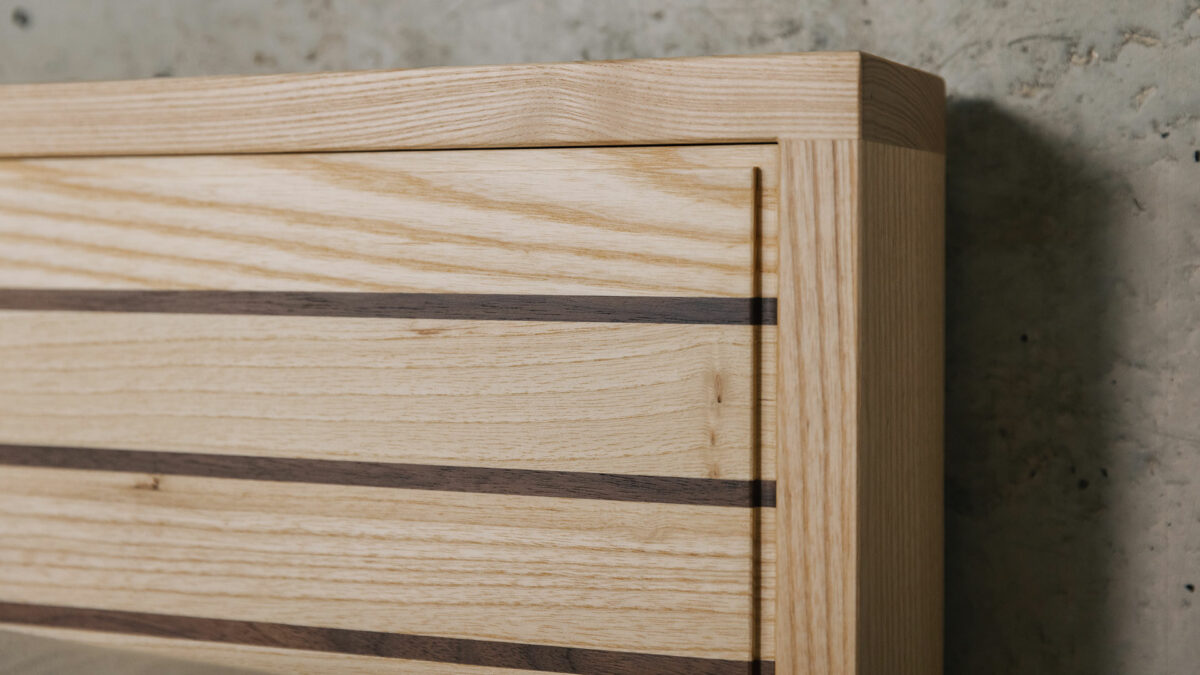 A special edition Leith bed in Ash wood with walnut stripes to the headboard panel a close up view