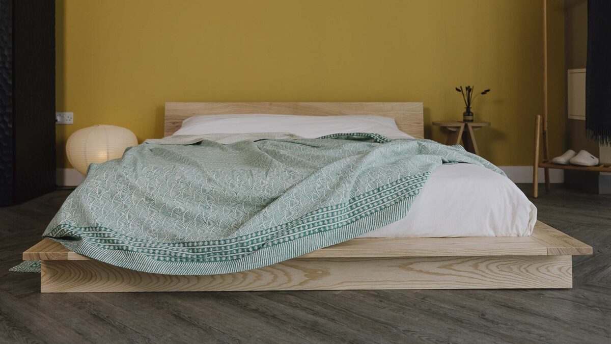Green kantha bedspread with wave pattern and bold, dark green border to the edges.