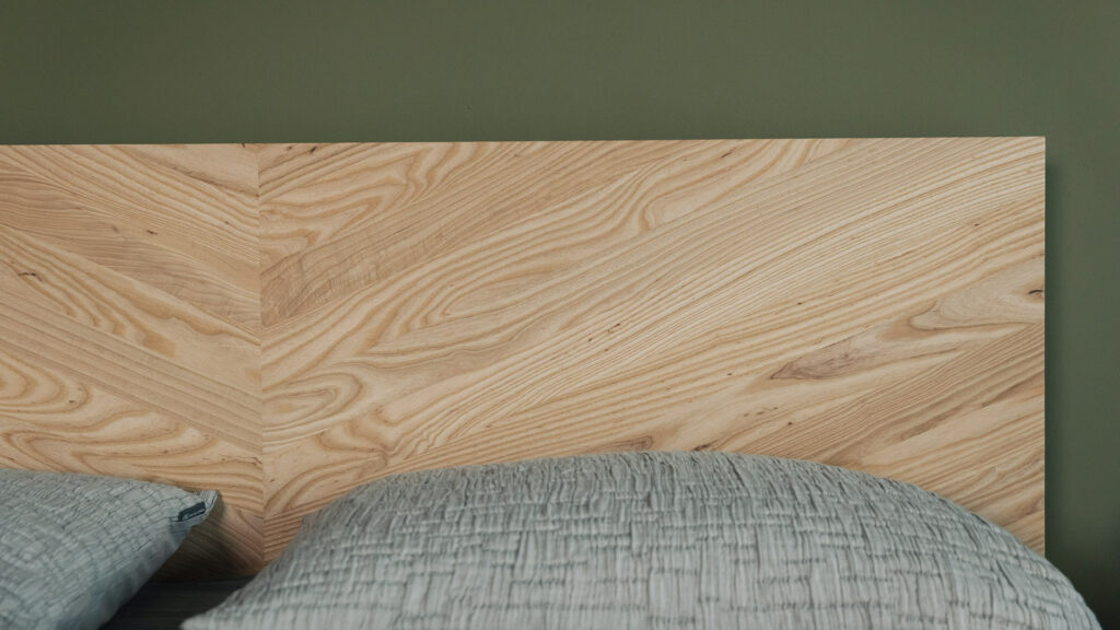 A handcrafted solid Ash Hathersage bed with chevron pattern headboard shown close up