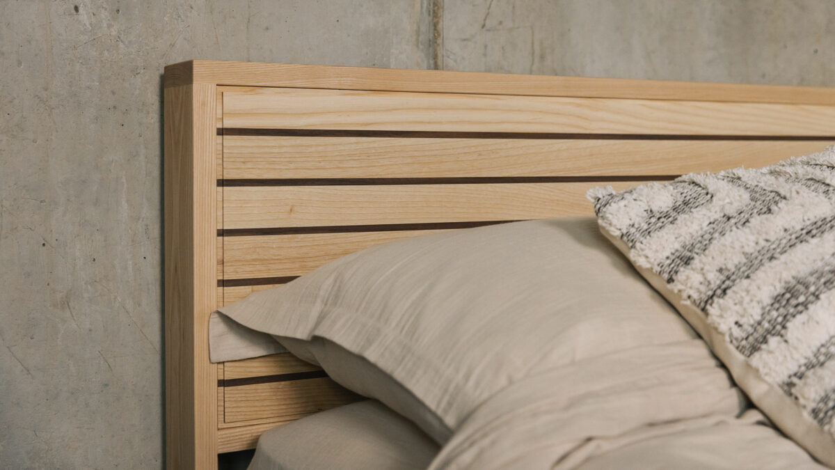 A special edition hand crafted Leith bed in Ash wood with walnut stripes to the headboard panel a close up photo