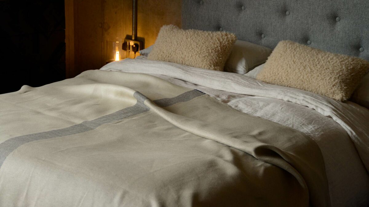 woven 100% Irish linen colour block throw in neutral stone colours shown on a kingsize bed