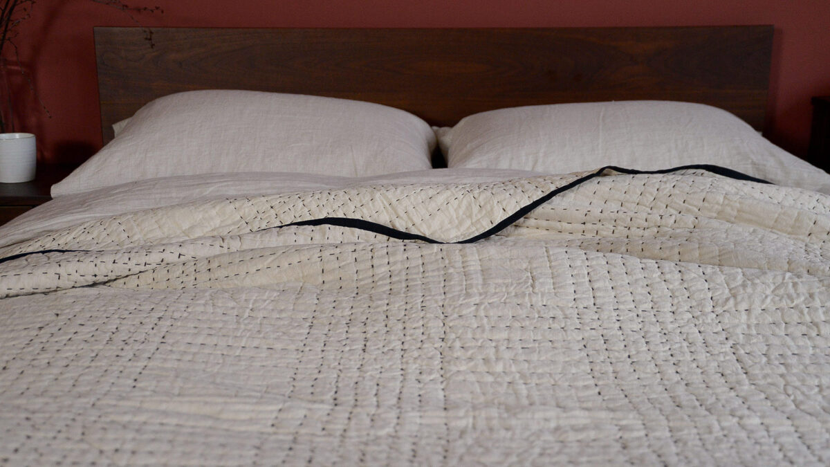 beige bedspread with black stitching and trim