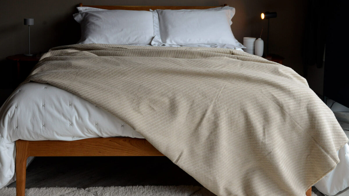 soft cotton striped bedspread in beige shown on a bed