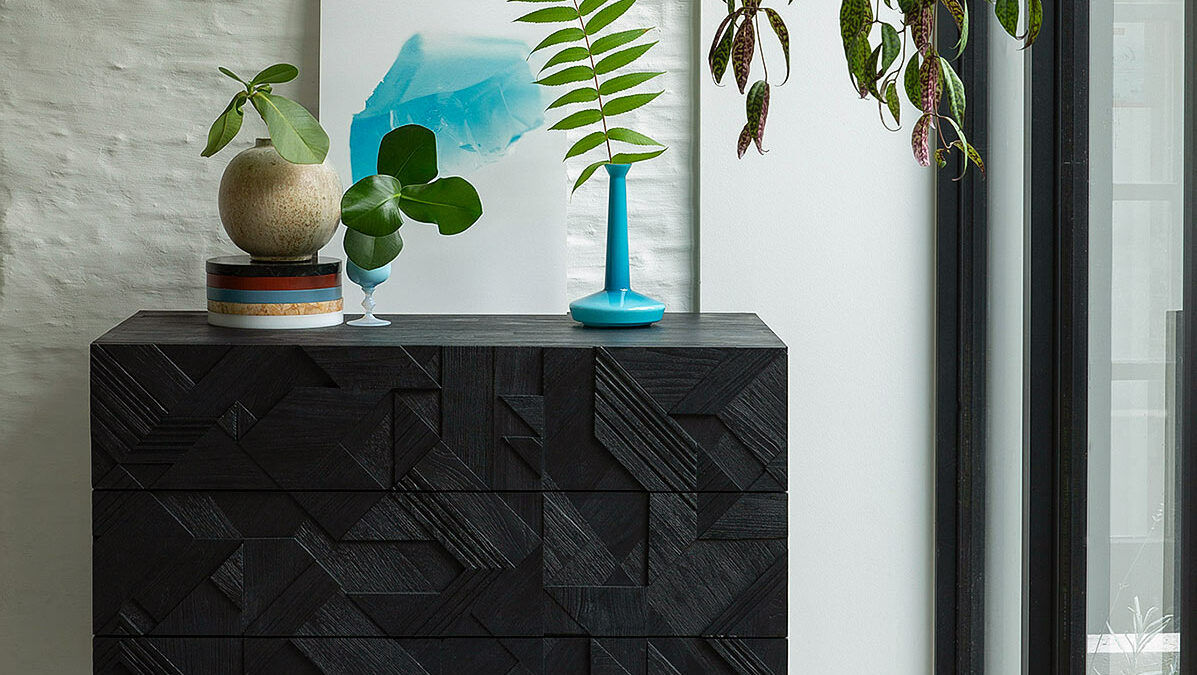 black teak chest of drawers with a carved graphic pattern