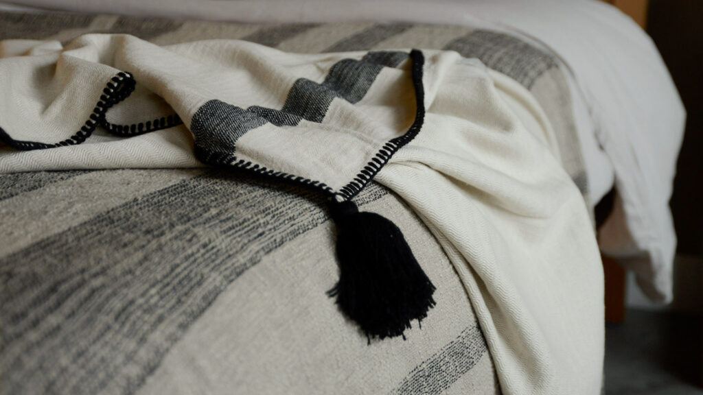 woven cotton throw in ivory and black with black tassel and stitched edge