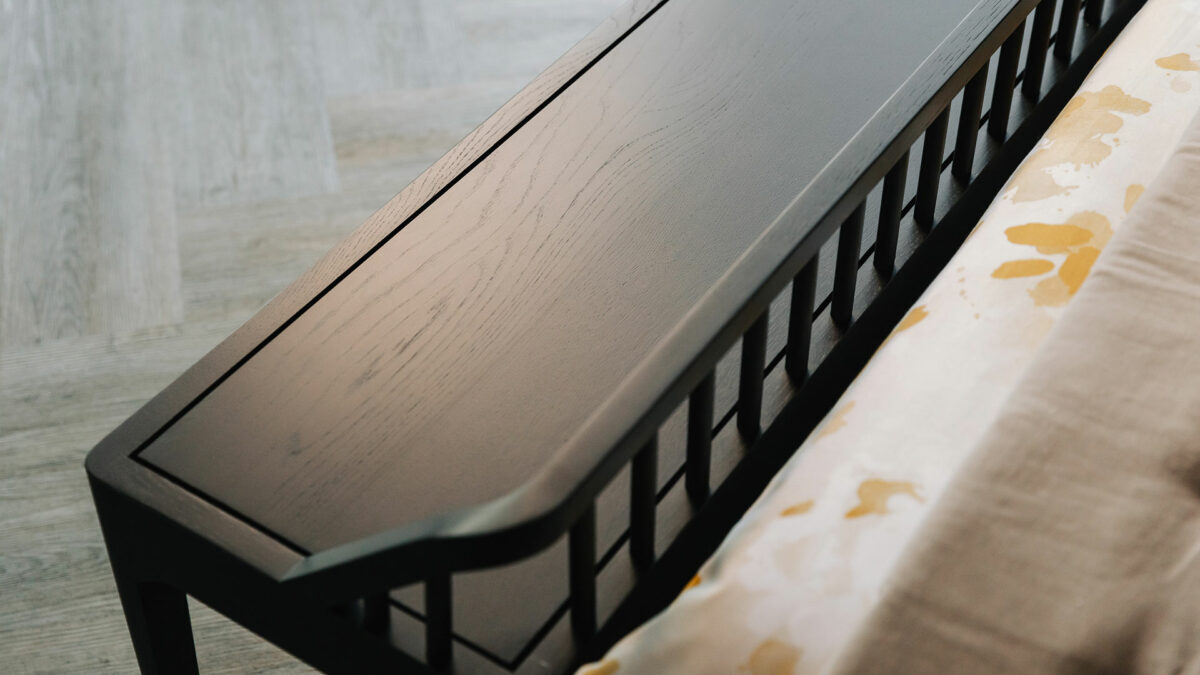 slender spindle bench in black oak and in detail, shown at the end of a kingsize bed