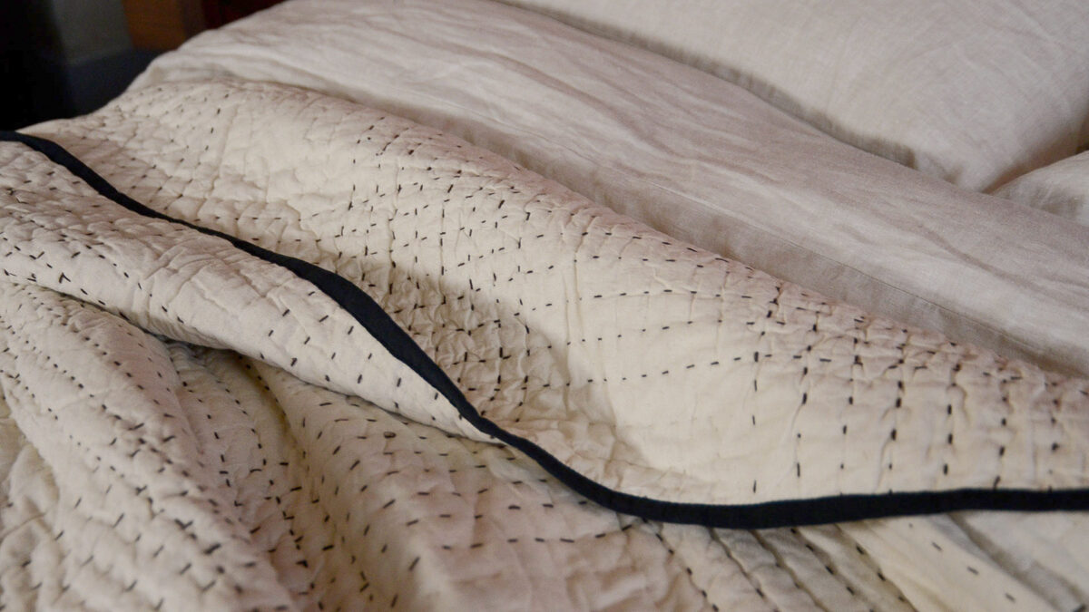 black trimmed stitched beige bedspread close up