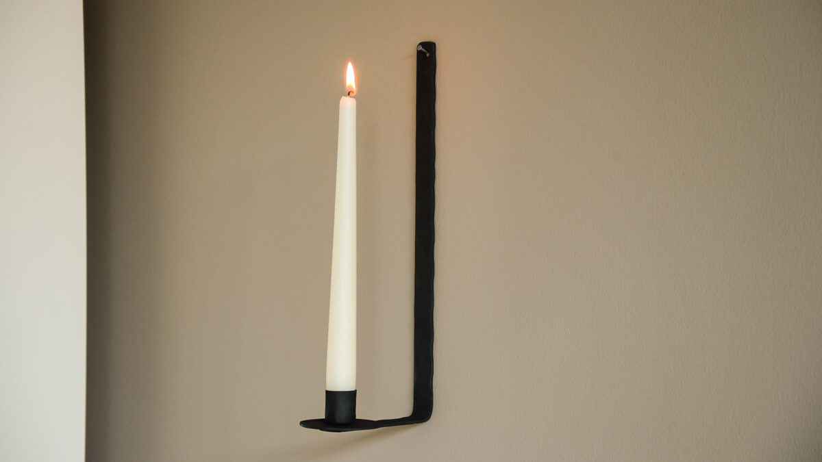 black wall mounted candlestick holder side view lit