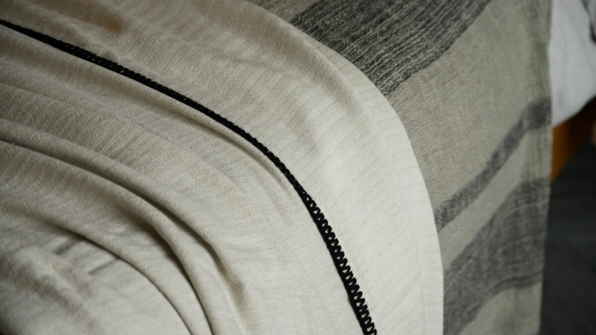 woven cotton throw in ivory and black with black tassel and stitched edge