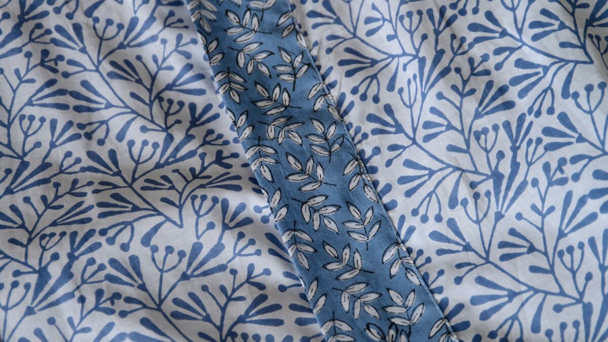 a close up of the lightweight cotton kimono with a block print leaf design in blue and white and with contrast belt and cuffs