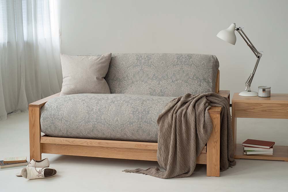 Oak Panama futon sofa bed with wool floral cover. Shown with Cube side table.