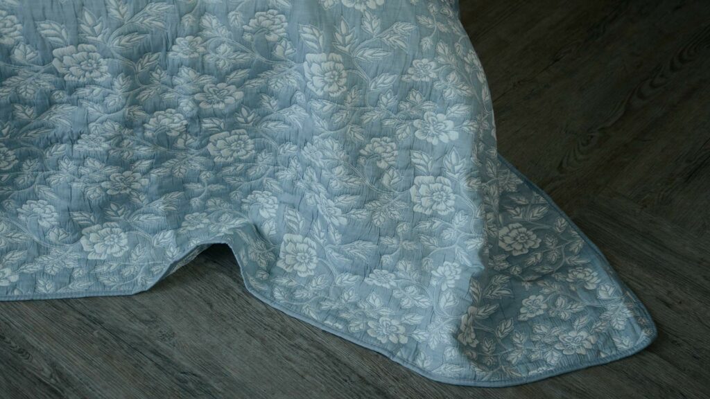 Wedgwood blue and ivory floral patterned reversible quilted bedspread shown close up