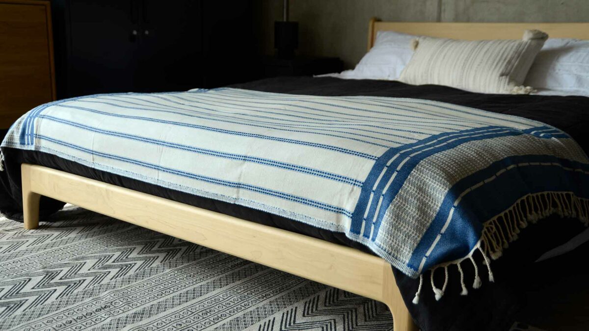 reversible blue and ivory coloured woven cotton throw shown on a bed