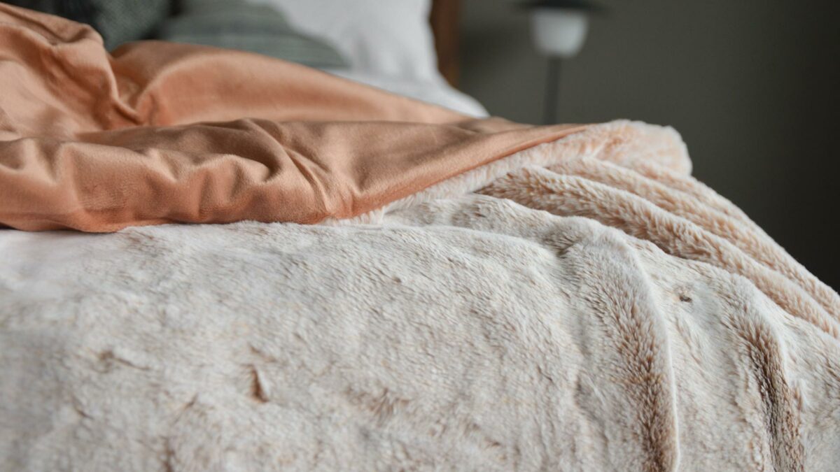 Frosted pink faux fur throw a view showing the reverse salmon pink velveteen fabric