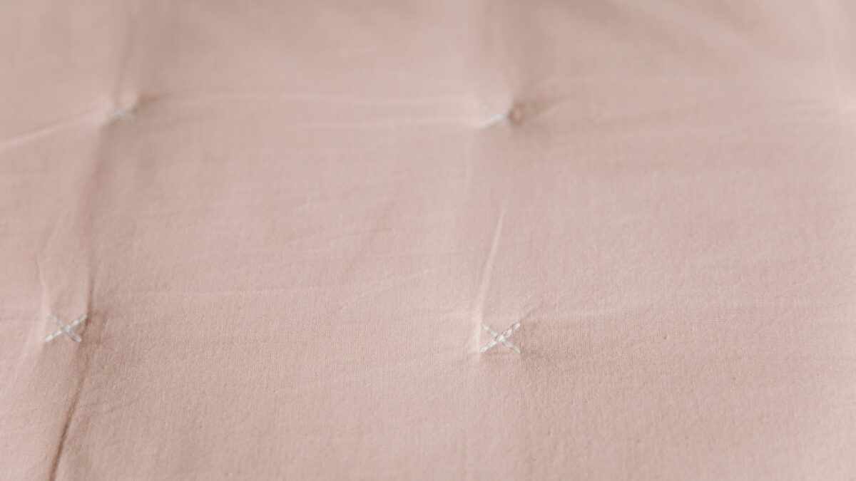 blush pink quilted cotton bedspread shown close up to see the cross stitches of the quilting