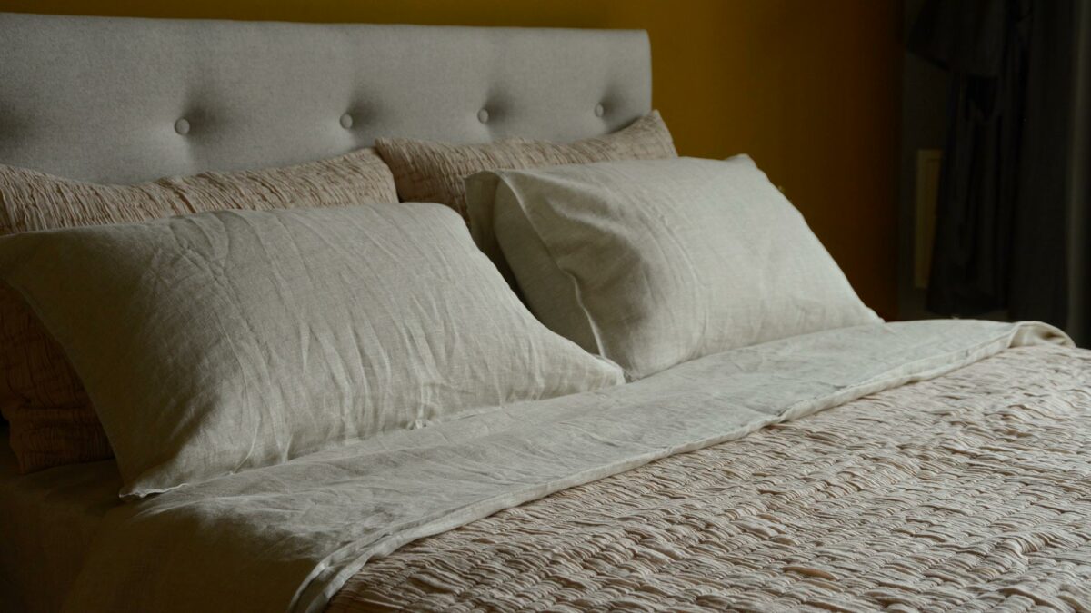 lightly quilted and textured crinkle effect bedspread and pillowcase set in blush pink shown on a bed