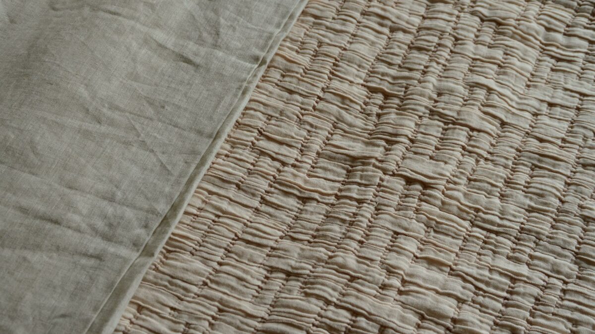 lightly quilted and textured crinkle effect bedspread in blush pink a close up view