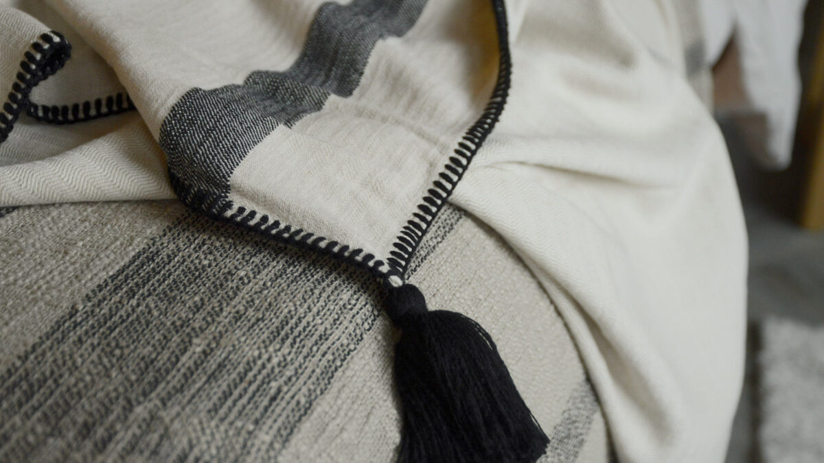 woven cotton throw in ivory and black with black tassel and stitched edge