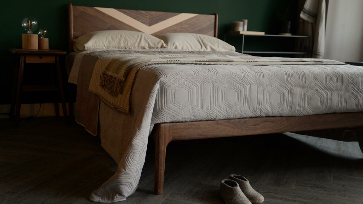 Hand made walnut Hoxton bed with bold chevron maple wood inlay shown from the foot end