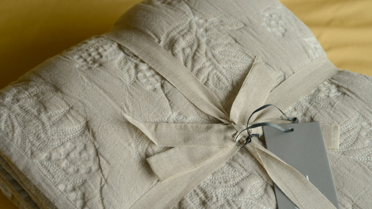 Embroidered quilted bedspread sand coloured one side ivory reverse, shown close up