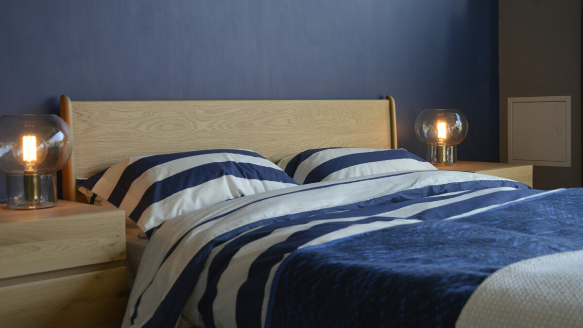 A closer view of the Carnaby bed headboard in Oak, shown with navy & ivory striped cotton duvet set.