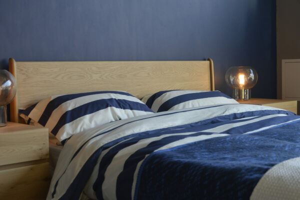 A closer view of the Carnaby bed headboard in Oak, shown with navy & ivory striped cotton duvet set.