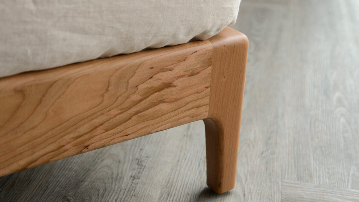 A close up look at the leg of a solid cherry wood Carnaby bed