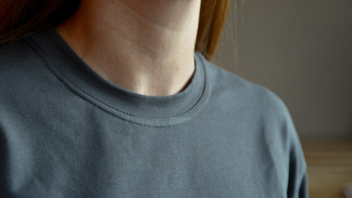 charcoal grey T shirt with silver glitter star motif shown on a model the neckline in close up
