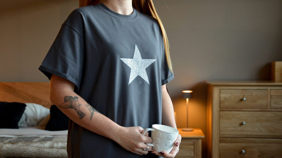 charcoal grey T shirt with silver glitter star motif shown on a model