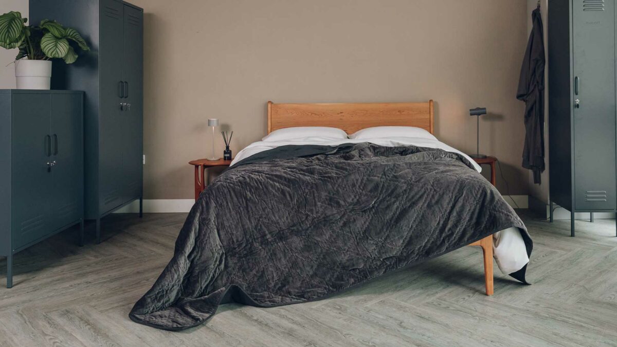 luxury quilted bedspread in charcoal grey velvet shown draped on a Kingsize cherry wood Camden bed