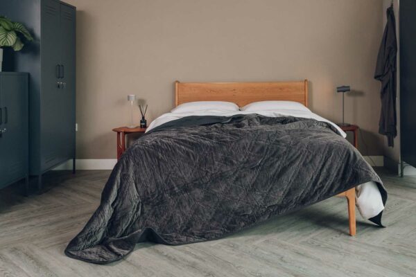 luxury quilted bedspread in charcoal grey velvet shown draped on a Kingsize cherry wood Camden bed