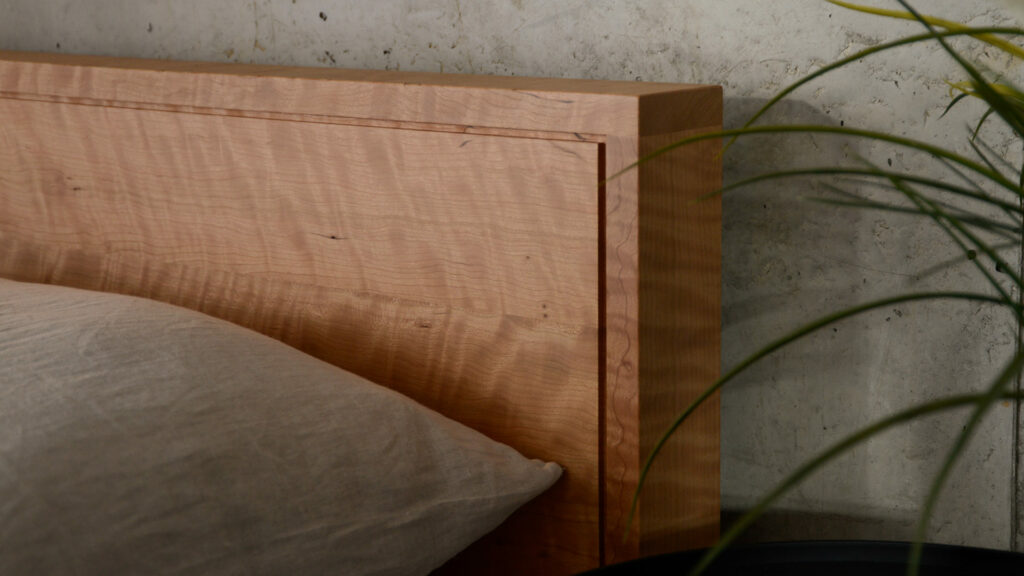 Leith bed headboard in solid cherry wood with a rippled grain a close up view of the corner