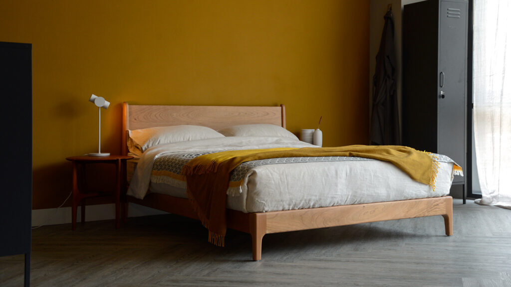 Our low hand made Carnaby bed made from cherry wood with ecru linen bedding and a mustard yellow throw