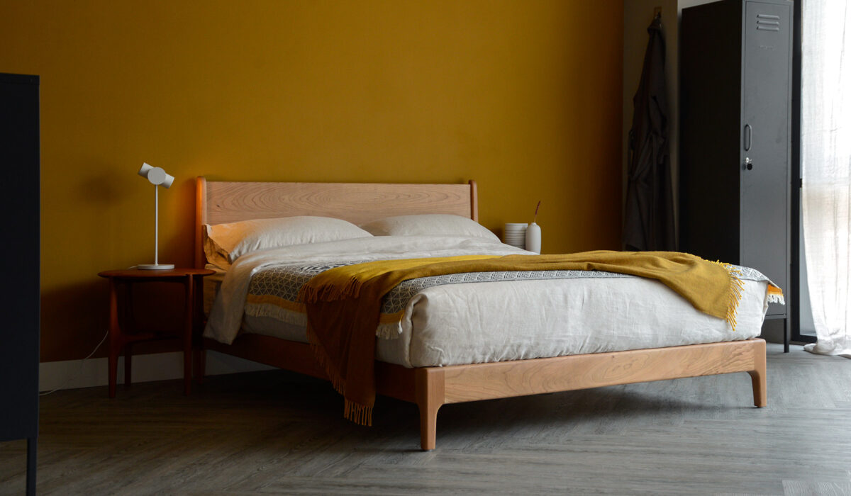 Our low hand made Carnaby bed made from cherry wood with ecru linen bedding and a mustard yellow throw