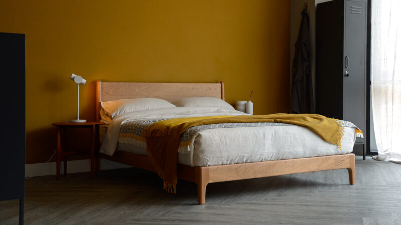 Our low hand made Carnaby bed made from cherry wood with ecru linen bedding and a mustard yellow throw