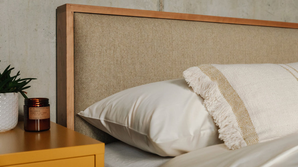 The upholstered headboard of the Shetland contemporary wooden bed in cherry