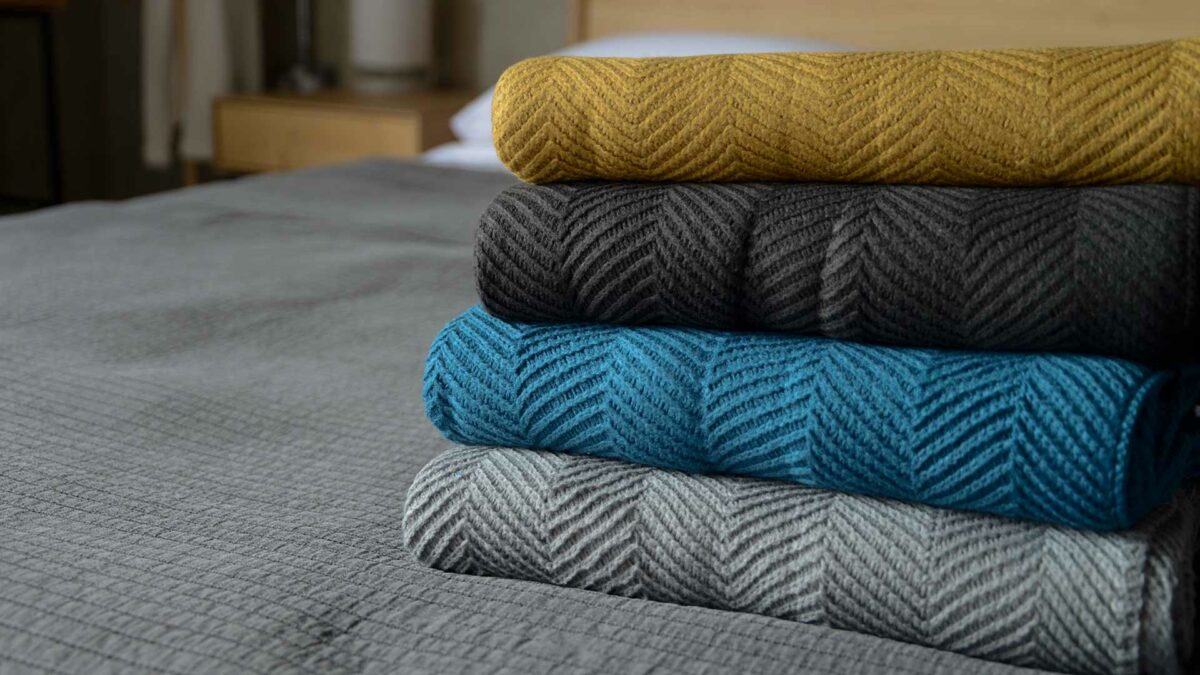 stack of soft knitted chevron pattern throws in a range of colours