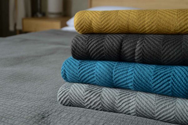 stack of soft knitted chevron pattern throws in a range of colours