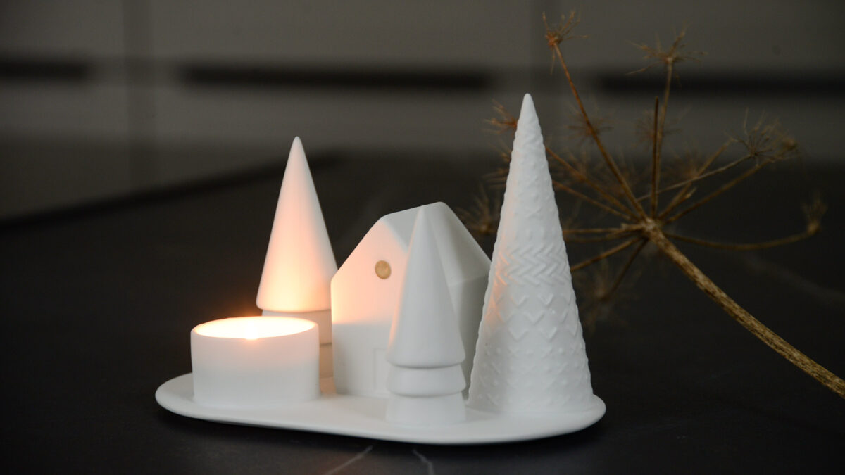 Snowy scene matt porcelain tea light holder with trees and a house and shown lit