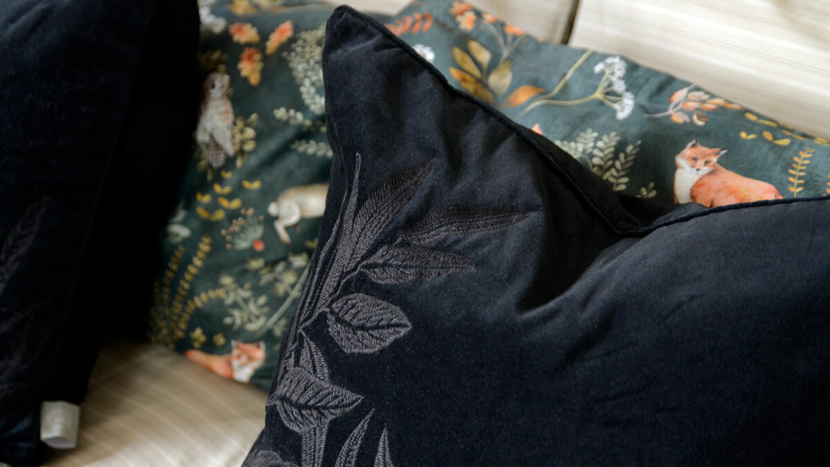 black velvet cushion with black embroidered leaves design a close up of the stitching