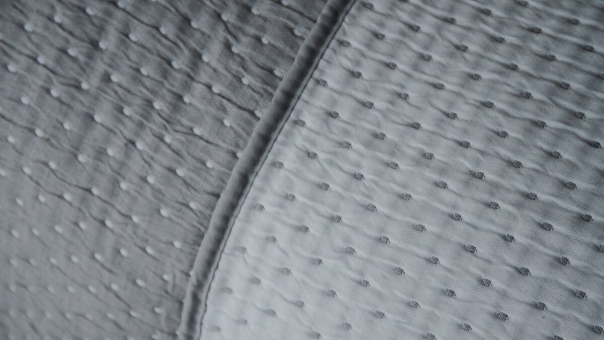 reversible stitched polka dot quilted bedspread in grey and white shown in close up