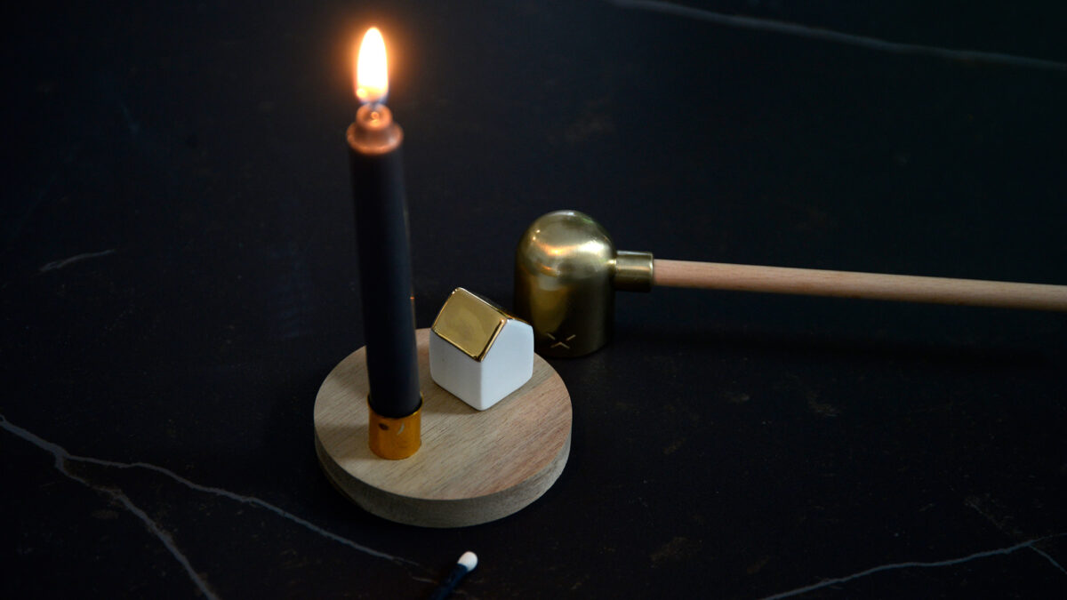 small candle holder with a wooden base and a porcelain house and with a wood handled candle snuffer