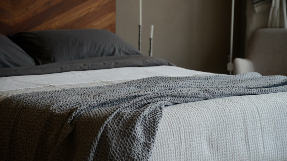 waffle weave cotton throw in a grey colour shown on a kingsize bed